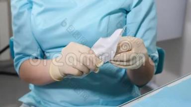 戴蓝色乳胶手套准备工作的女牙医特写镜头，用牙科无菌工具打<strong>开工</strong>艺包
